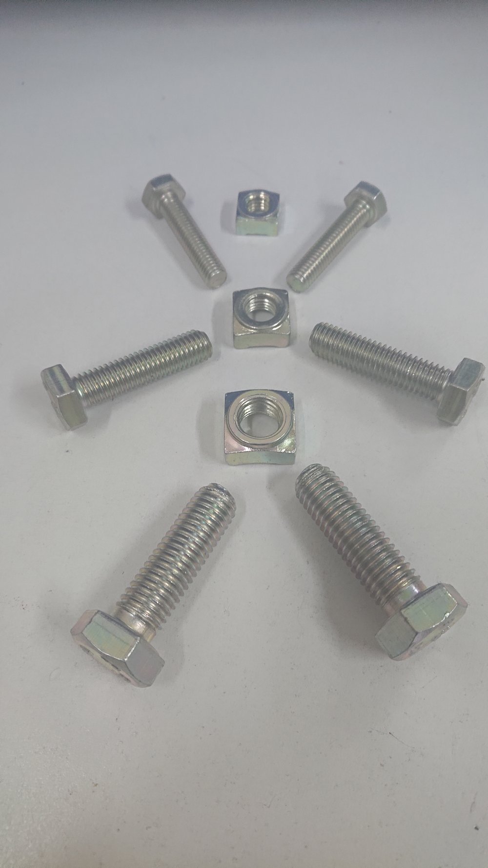 Mine Coated Bolts and Square Weld Nuts arranged on a workshop surface, showing the Mine Coat rust-resistant finish